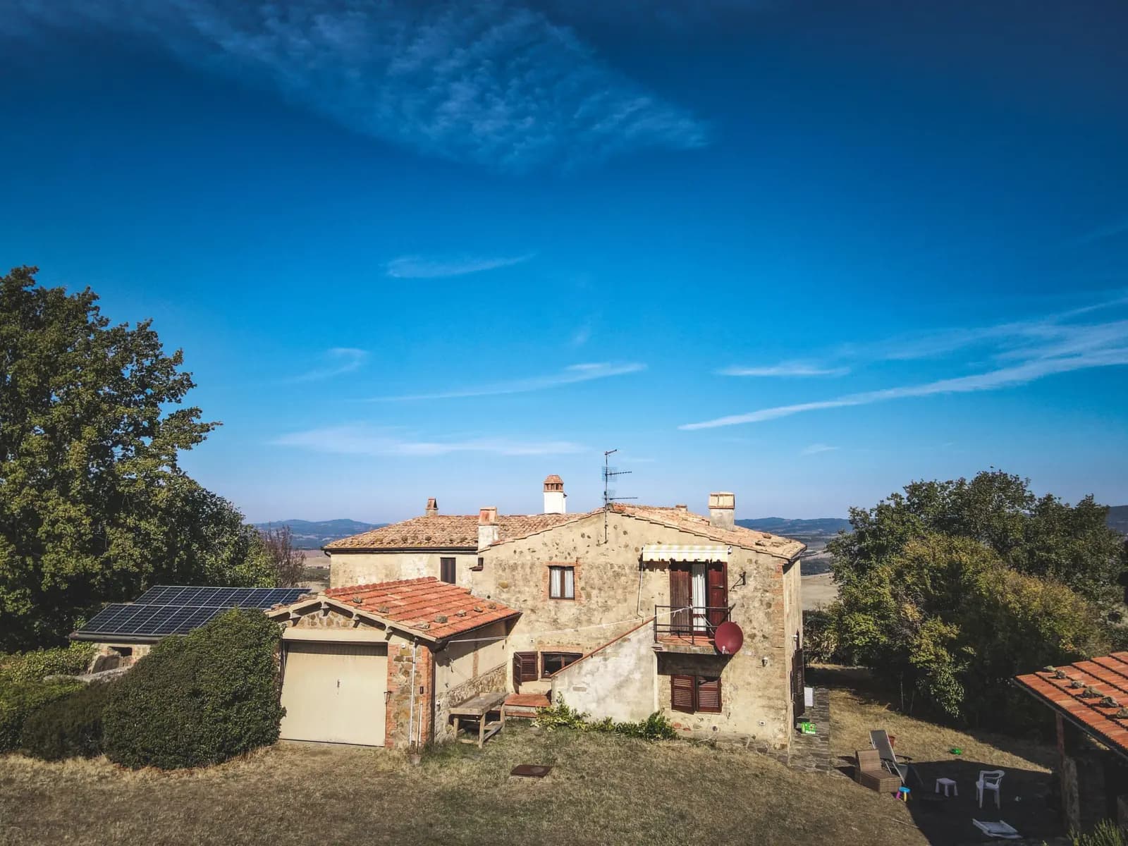 Maison en pierre sur une colline, des panneaux solaires sur le toit voisin