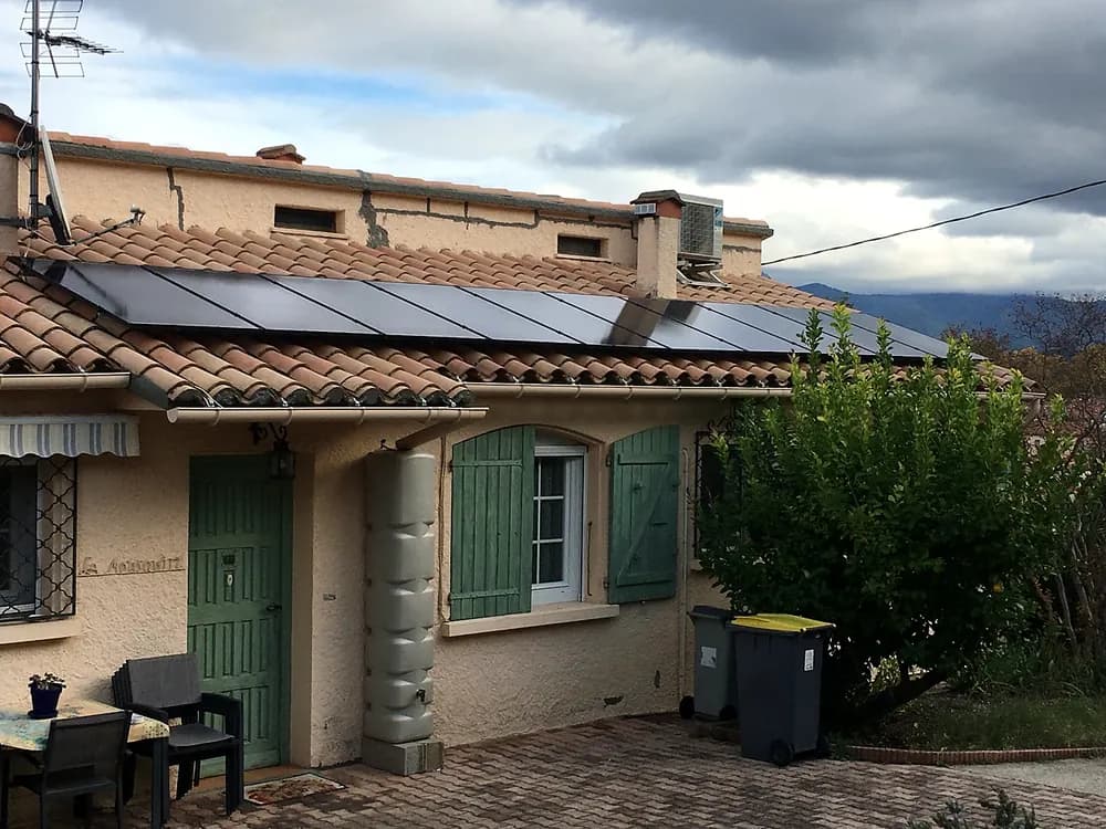 Maison aux volets verts, panneaux solaires sur le toit en tuiles