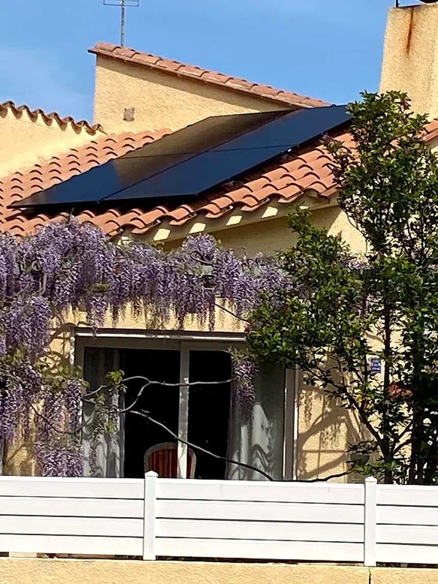 Maison avec glycine, panneaux solaires noirs sur le toit en tuiles