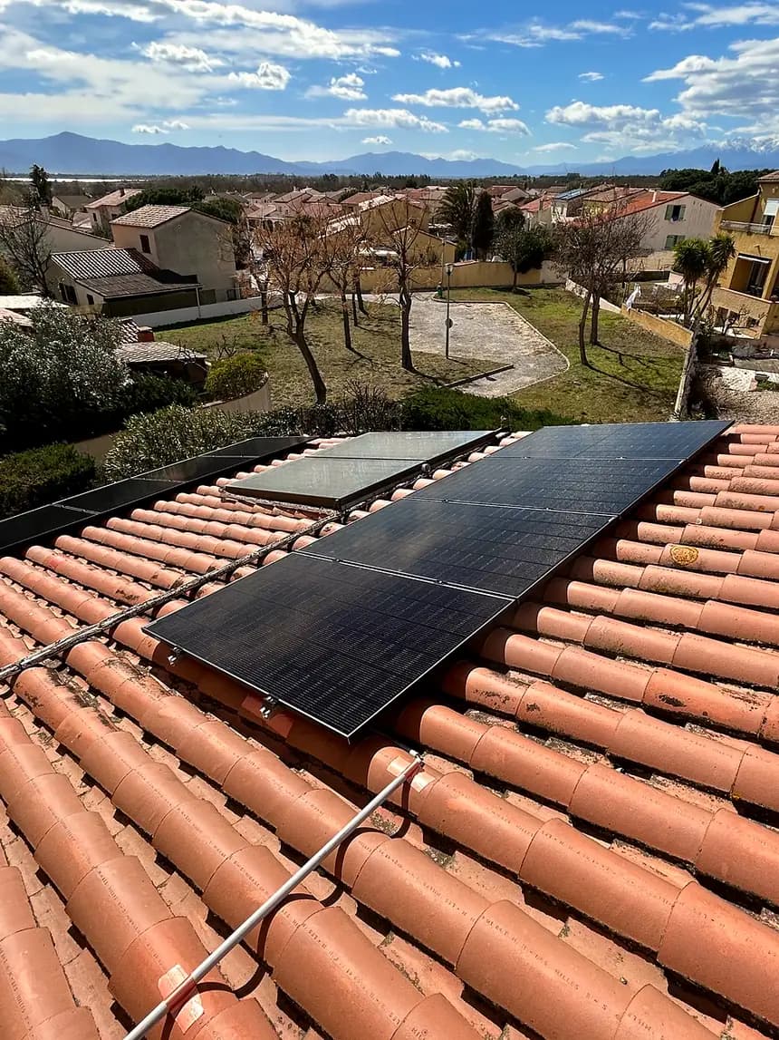 Panneaux solaires sur tuiles canal, montagnes à l’horizon