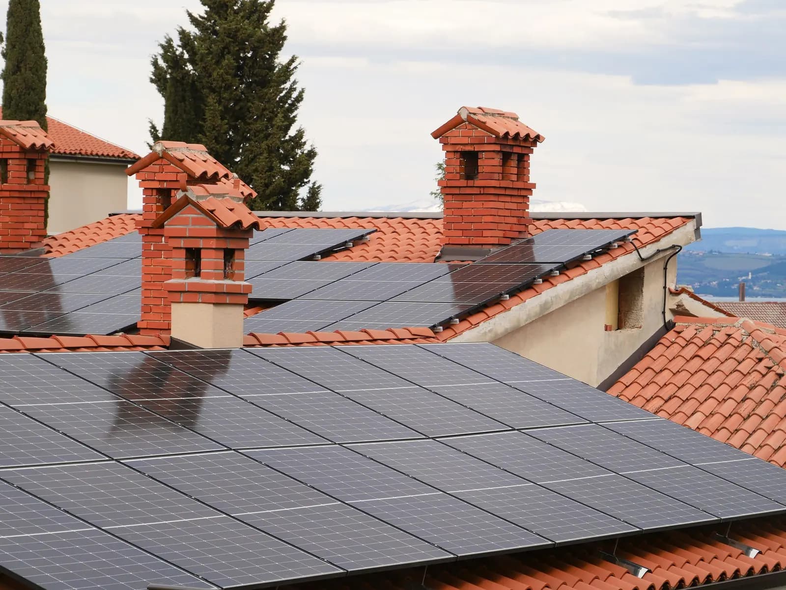 Panneaux solaires sur des toits de tuiles rouges à cheminées